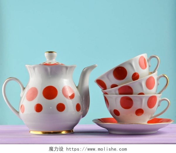 蓝绿色背景前的紫色桌子上有着一套茶具陶瓷茶壶, 一叠波尔卡圆点的杯子, 放在蓝色柔和背景上的木桌上。复制空间